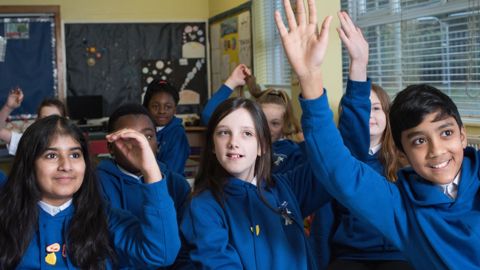 pupils in classroom raising their hands