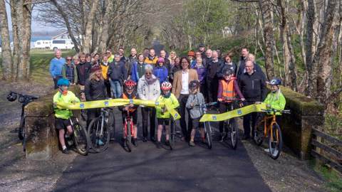 Group of people cutting the ribbon at opening of new walking and cycling path