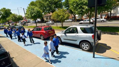 young children in uniform walking to school on a wide path, painted light blue