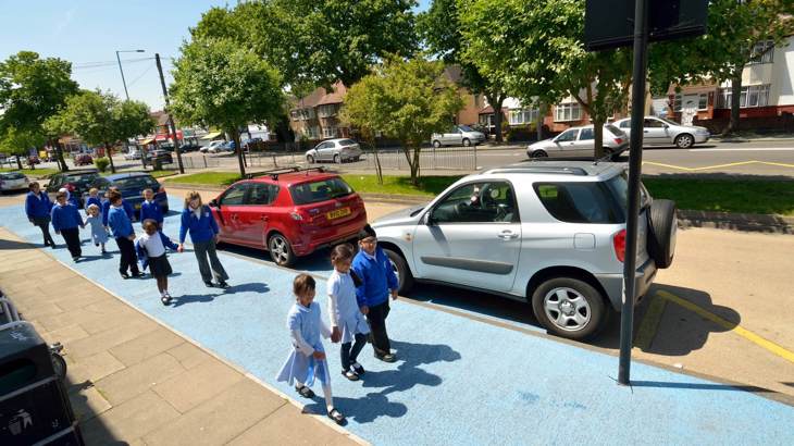 young children in uniform walking to school on a wide path, painted light blue