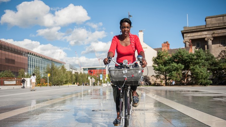 A women cycles through birmingham on a warm sunny day