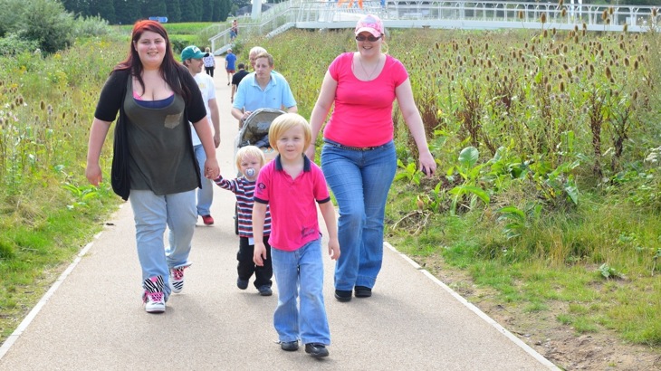 A family walk together along a traffic free route surrounded by bushes