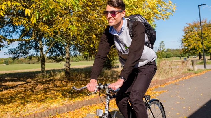 A young man cycles along a cycle route on a sunny autumnal day