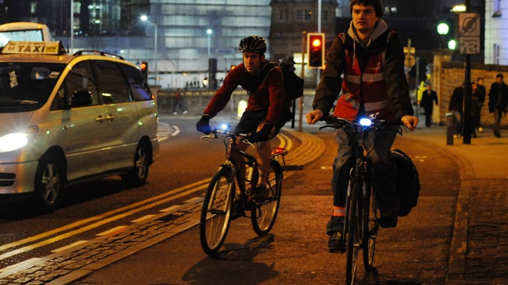 Two men cycling in the dark in a busy city landscape
