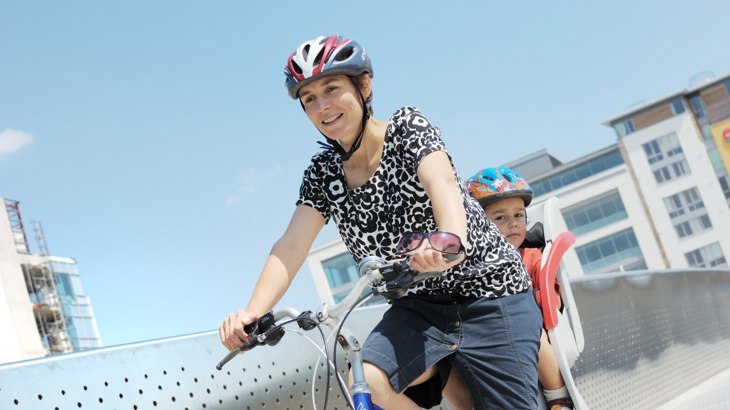 Mum cycling with child in bike seat behind her