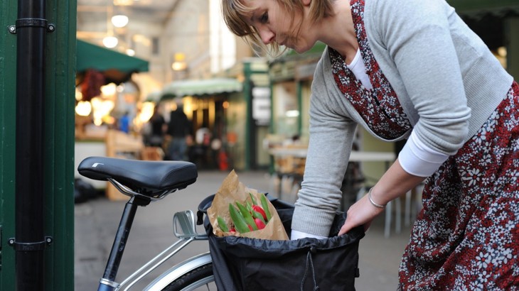 A woman packs her panniers on the side of her bike after doing some shopping