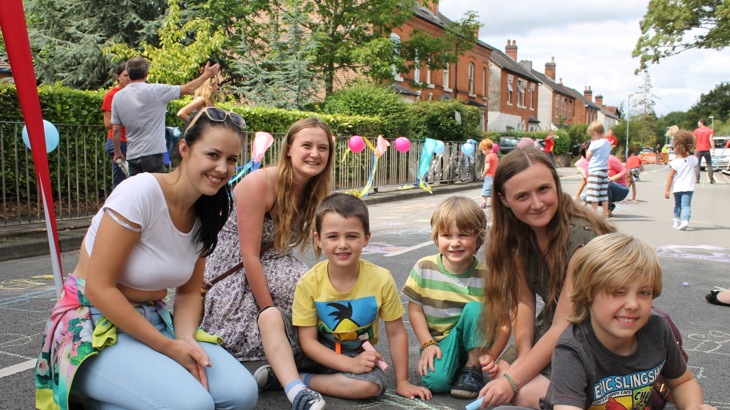 Families drawing on the street of a street party closure
