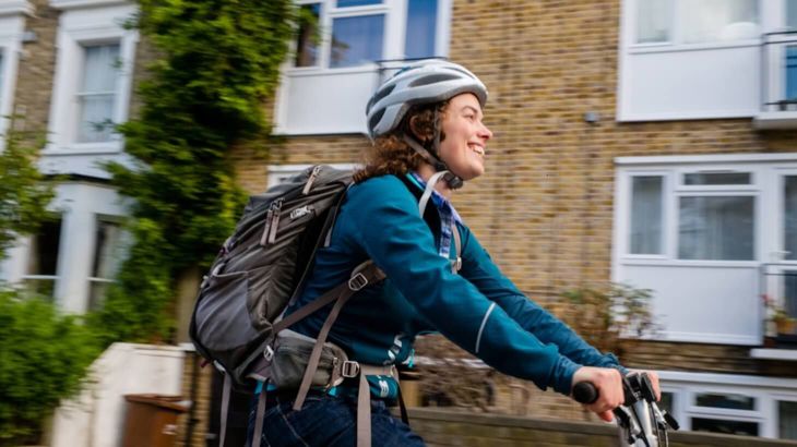 Woman cycling on residential street wearing helmet and backpack