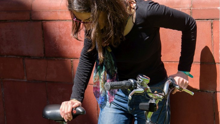 Woman checking saddle and handlebars on bike