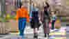 Three women walk along a street with brightly coloured artwork visible on the ground at Union Street, Dundee.