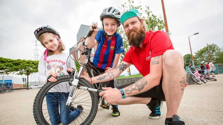 bike mechanic using pump to inflate Tyre with children