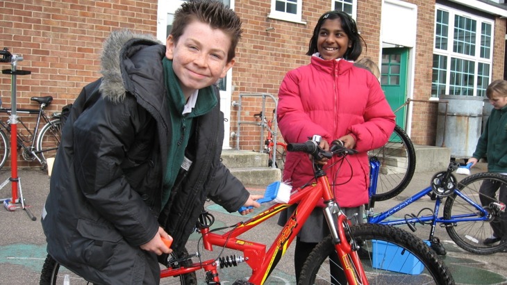 schoolboy cleaning bicycle with brush