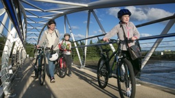 Family walking with bicycles over a bridge