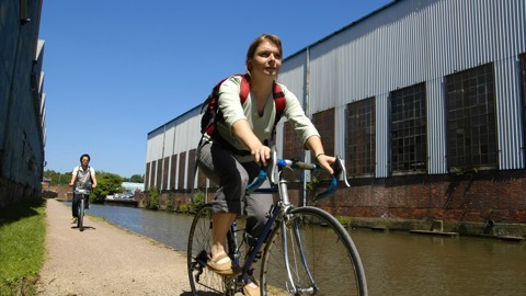 Two cyclists on canal towpath in industrial area