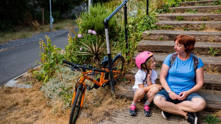 Mum and daughter sitting on steps with bicycles nearby