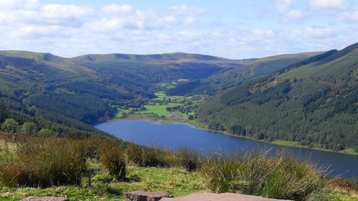 View of reservoir in Wales surrounded by mountains and trees