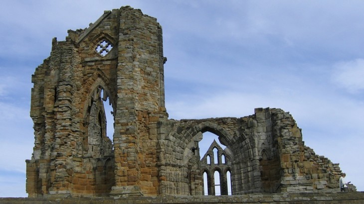 Wall of ruined Gothic abbey against blue sky