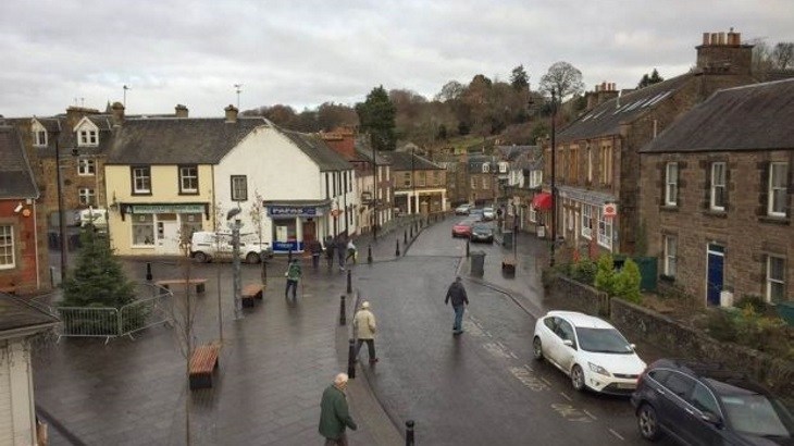 Town centre in Scottish town with Christmas tree, walkers and two parked cars