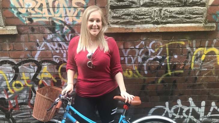 Gwyneth poses with her bike in front of a wall