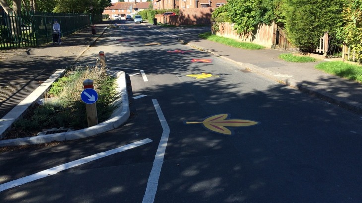 Embleton road after the project was completed. Flowers line the road which has been painted with colourful illustrations