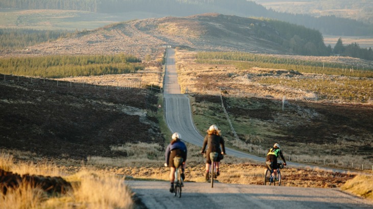 Three cyclists on road through Scottish countryside