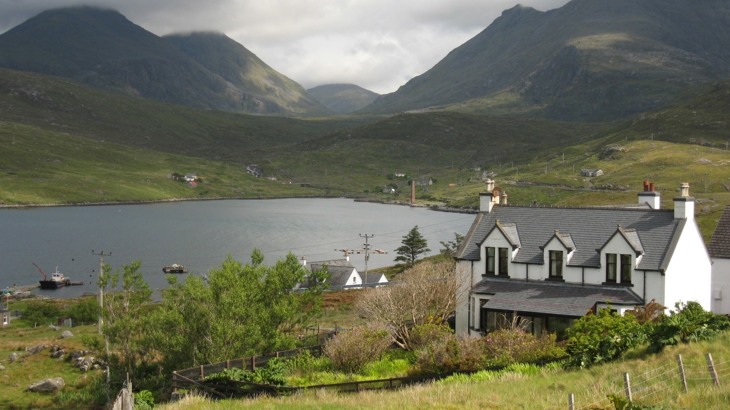 White house overlooking lake with mountains in the background