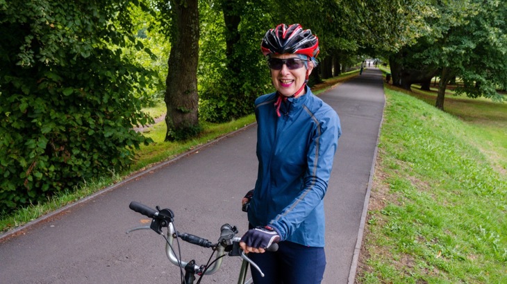 A female poses with her bike in a park
