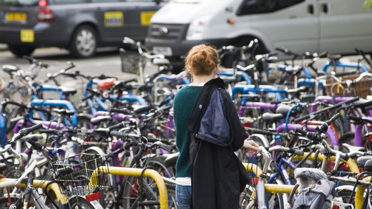 A Woman Unlocking Her Bike At A Bike Parking Stations In Oxford