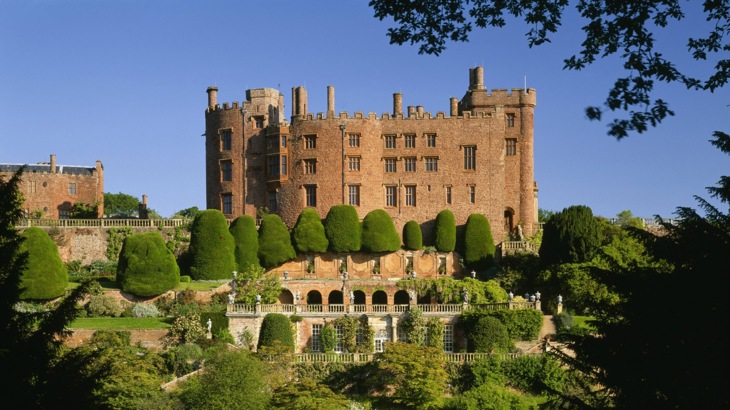 Red brick castle-style mansion in front of formal gardens