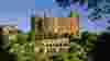 Red brick castle-style mansion in front of formal gardens