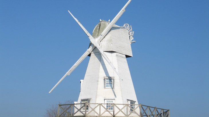 White wooden windmill against blue sky