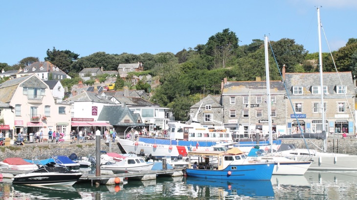 Town harbour with yachts and smaller boats, with shops and houses surrounding the harbour