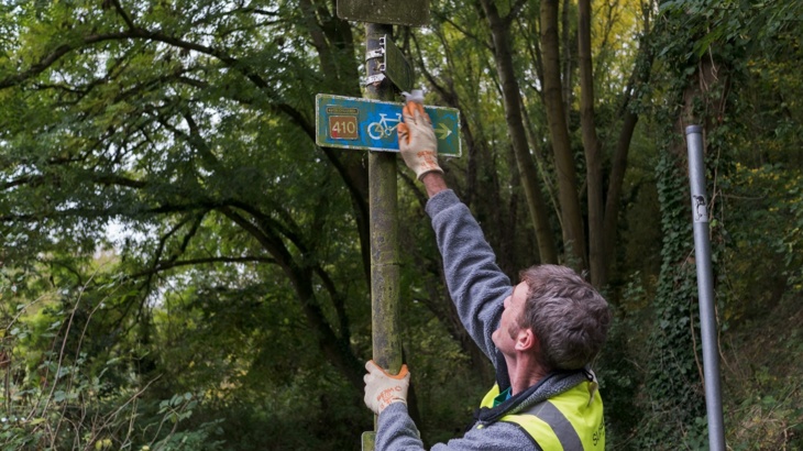 A volunteer cleaning a National Cycle Network sign