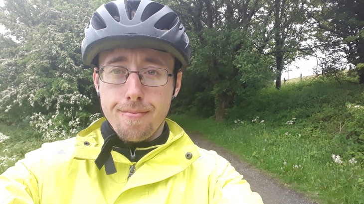 Man wearing glasses, black cycling helmet and high-vis jacket
