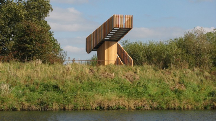 Wooden viewing platform on grassy bank by waterway 