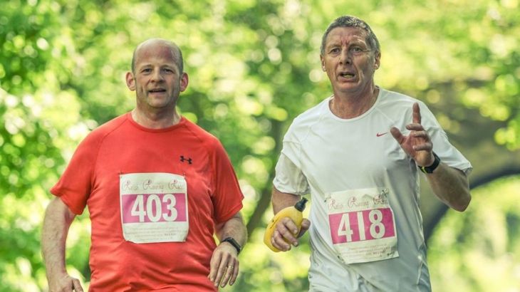 Two men in running race with runner number stickers on their shirts