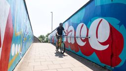 man cycles through underpass with colourful mural