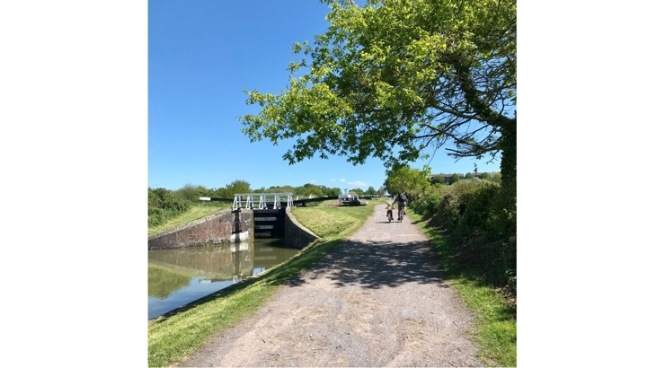Adult and child cycling along canal towpath with locks to the side