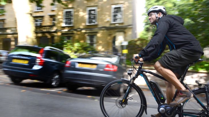 A man rides an e-bike up a hill in a residential area