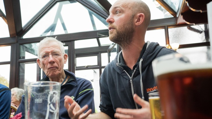 Two men sat in pub with pint glasses and beer 