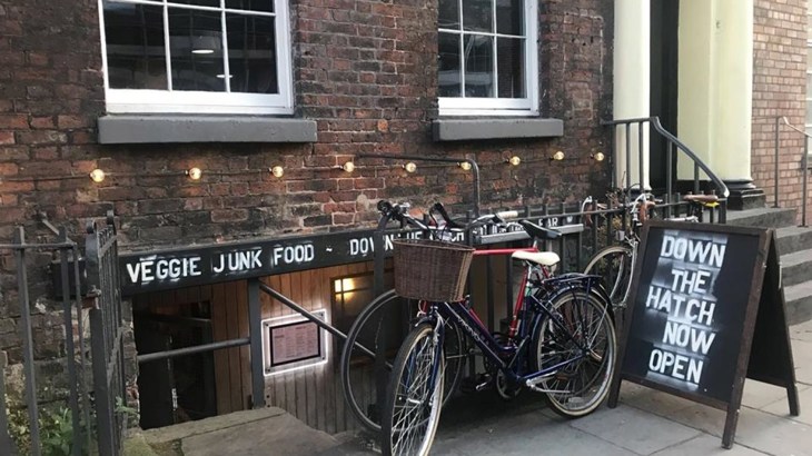 Two bikes on railings outside basement cafe on urban street