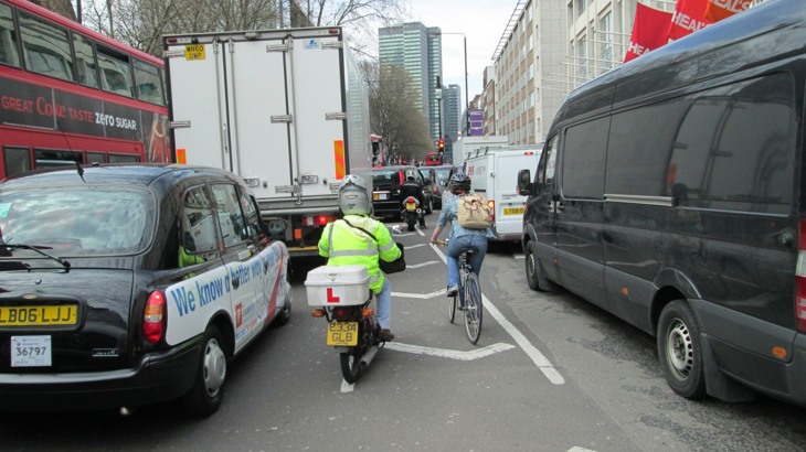 A person on a bicycle tries to navigate through congestion in London