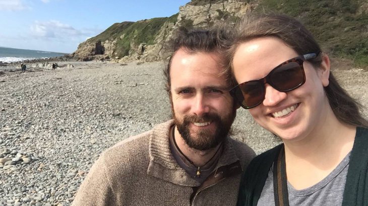 Kristen wearing sunglasses pictured with her husband on a beach
