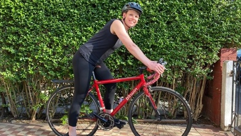 Kirsten, wearing a helmet and stood with her bike smiling at the camera