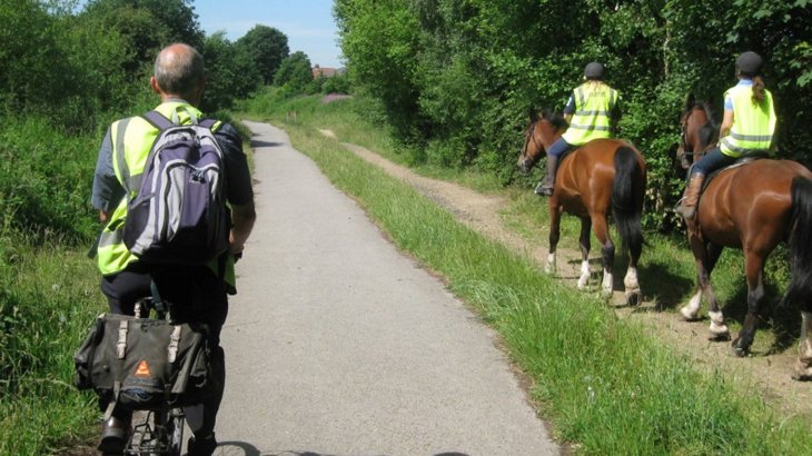 Person cycling passing by two horse riders on a traffic-free route