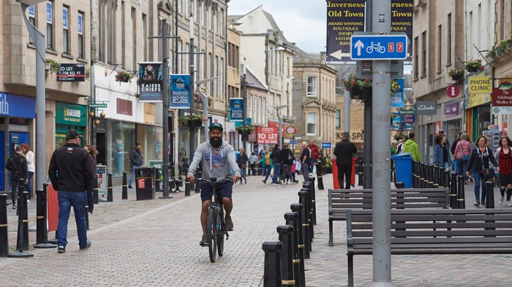 Man cycling down high street
