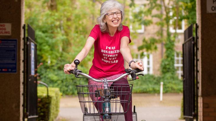 Lady smiling as she rides her trike through an archway