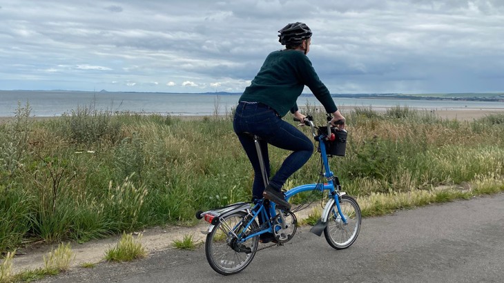 Tierney cycling on her blue e-bike along the coast