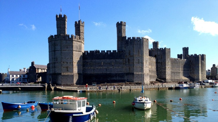 A medieval castle looking over a harbour with boats