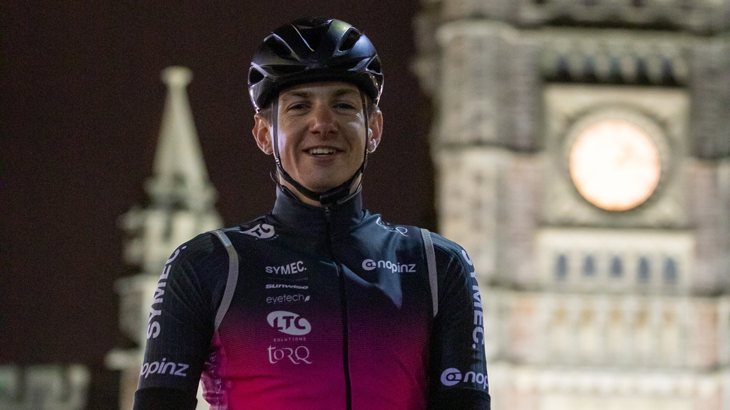 Tom standing with his bike and helmet at Bristol Temple Meads in the dark